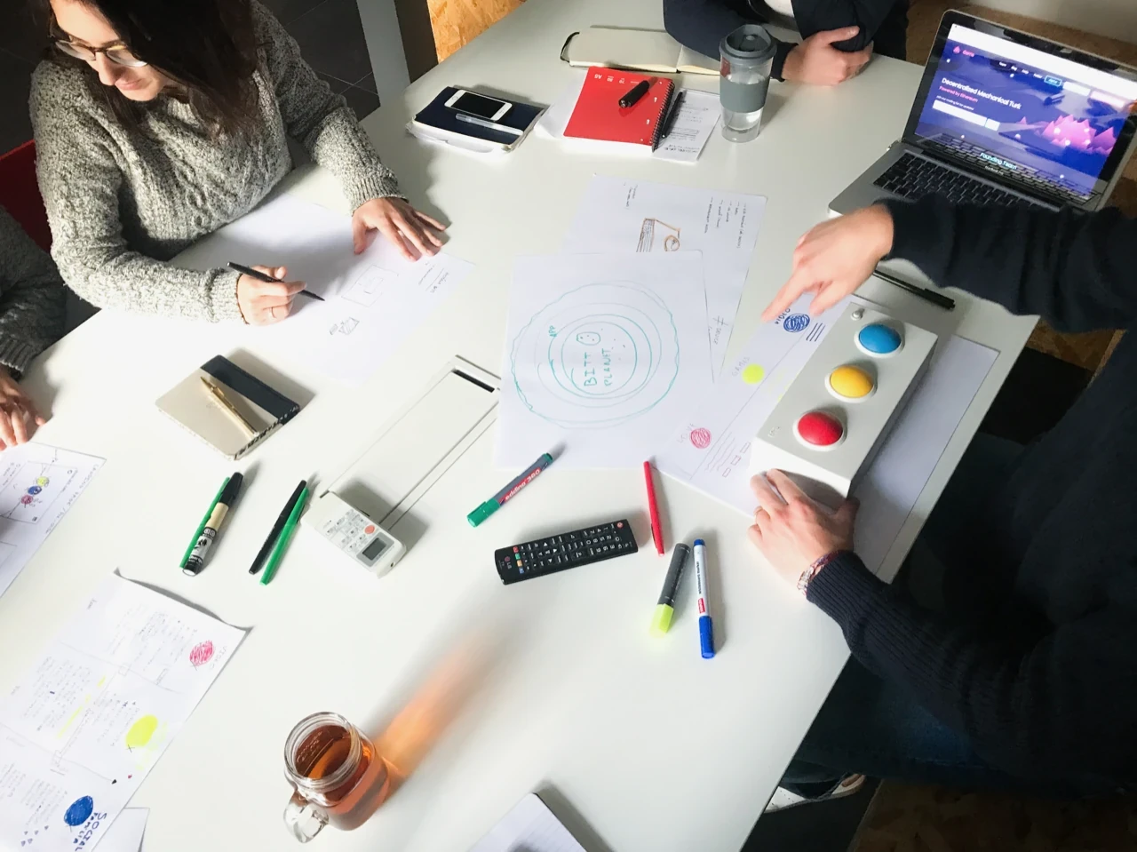 Workshop overhead: team sketching around BITI prototype with coloured buttons