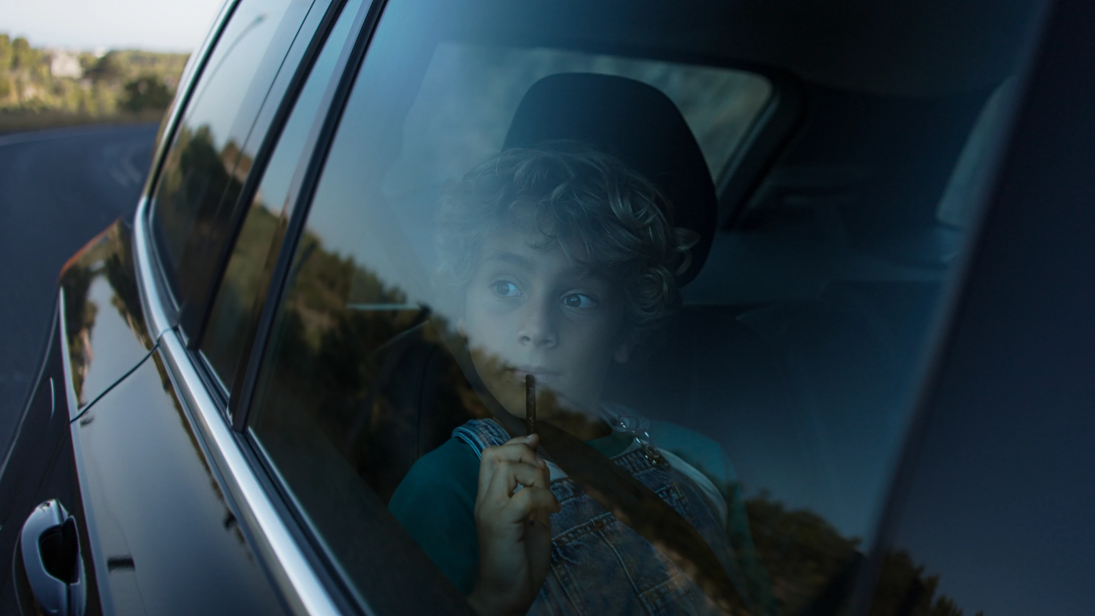 Child looking through car window with pencil in hand